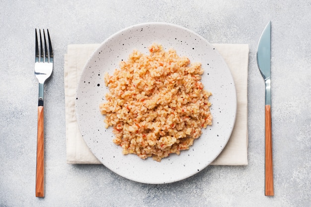 Bulgur hervido con tomates en un plato de cerámica.