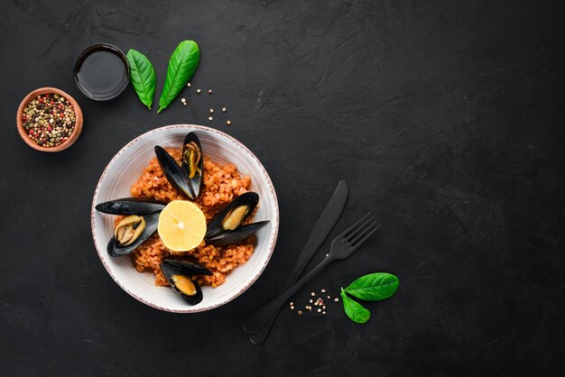 Bulgur mit Muscheln und Tomatensauce in einem Teller auf dem alten Hintergrund Draufsicht Freier Platz für Ihren Text