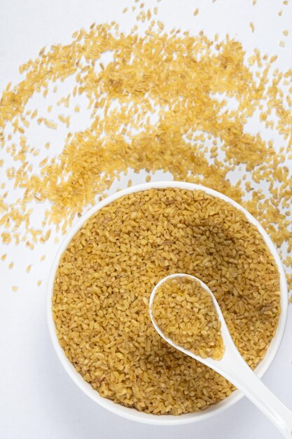 Bulgur não cozido quebrado de trigo em uma colher e placa vista de cima
