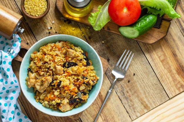 Bulgur con pavo y ciruelas pasas se sirve con verduras frescas en una mesa rústica Espacio de copia