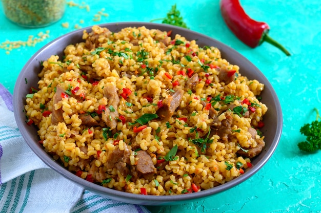 Bulgur con pollo y verduras. Deliciosa ensalada caliente saludable sobre un fondo brillante. Bulgur pilaf. De cerca