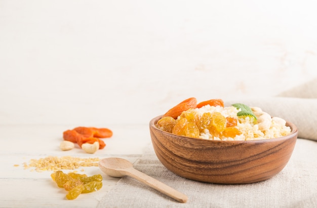 Bulgurbrei mit getrockneten Aprikosen, Rosinen und Cashewnüssen in Holzschale