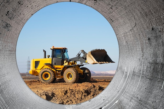 Bulldozer o cargador mueve la tierra en el sitio de construcción contra el cielo azul Una máquina de movimiento de tierras está nivelando el sitio Construcción de equipo pesado para movimiento de tierras