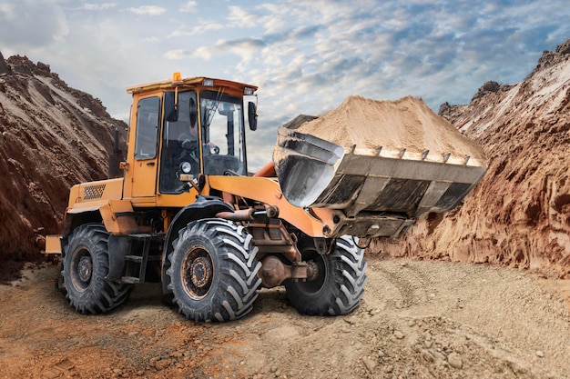 Bulldozer o cargador que mueve arena en un sitio de construcción en un pozo Una máquina de movimiento de tierras está nivelando el sitio Equipo pesado de construcción para movimiento de tierras Mejora del territorio