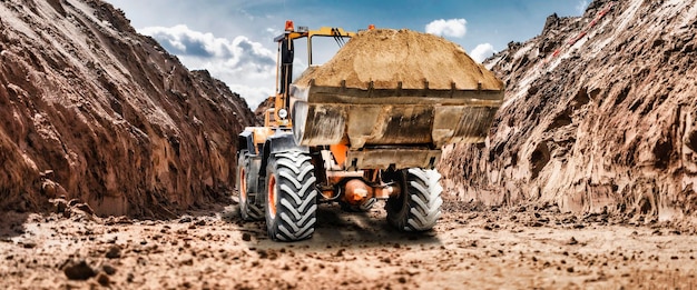 Bulldozer o cargador en un sitio de construcción en una cantera que transporta arena Potente cargador de ruedas o bulldozer con un cucharón grande en un sitio de construcción Equipos de construcción para movimiento de tierras