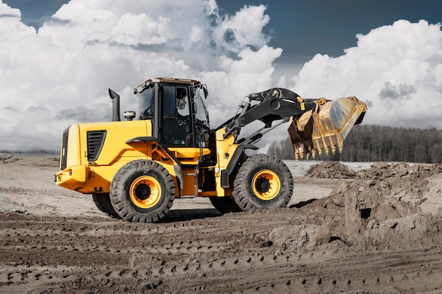 Bulldozer oder Lader bewegt die Erde auf der Baustelle gegen den blauen Himmel Eine Erdbewegungsmaschine nivelliert die Baustelle Schwere Baumaschinen für Erdarbeiten