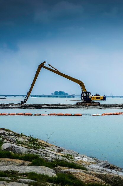 Bulldozer por el río contra el cielo