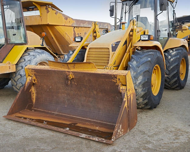 Bulldozers en un sitio de construcción estacionado después de operar un enorme vehículo naranja de construcción potente con una pala de pistón hidráulico y ruedas negras Maquinaria pesada afuera en un espacio vacío