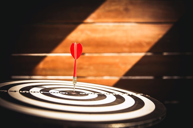 Bullseye o Bulls eye target o dartboard tiene un lanzamiento de flecha de dardo que golpea el centro de un tiroteo para la planificación de objetivos de negocios financieros y tiene como objetivo el objetivo ganador del concepto de negocio