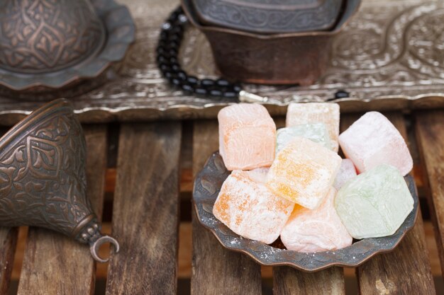 Bultos de Lokum o delicias turcas en un jarrón de cobre tradicional sobre mesa de madera