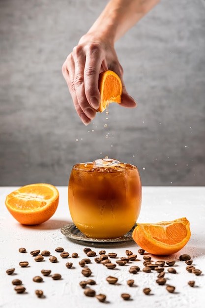 Bumble bebida de café refrescante com suco de laranja espremido na hora e gelo na preparação Espremendo uma fatia de laranja