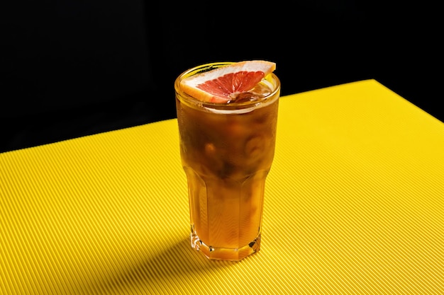 Foto bumble café bebida refrescante fría en un vaso alto adornado con una rodaja de pomelo sobre fondo amarillo