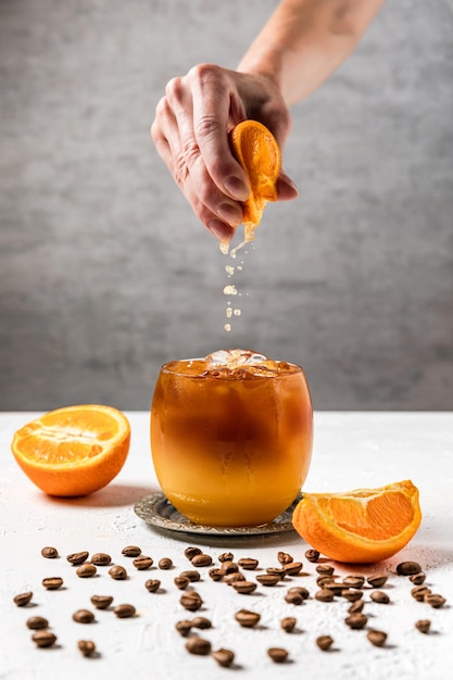 Bumble kaltes, erfrischendes Kaffeegetränk mit frisch gepresstem Orangensaft, Espresso und Eis in der Herstellung. Auspressen einer Orangenscheibe