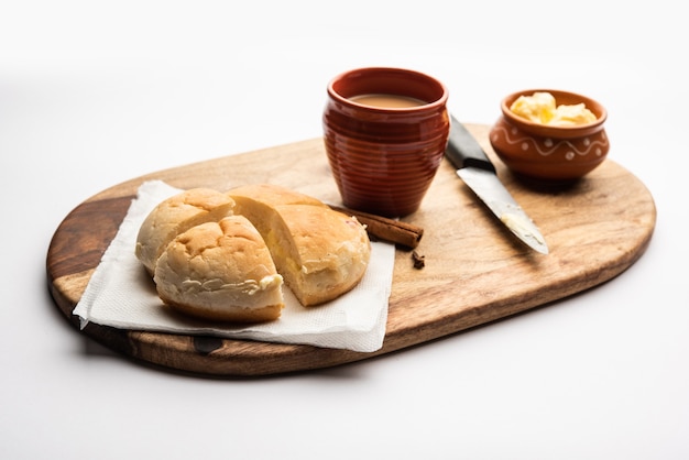 Bun-Maska-Tee oder Brötchen Maska Chai-Kombination enthält ein leicht süßes Brötchen, das mit Rosinen übersät ist, die in zwei Hälften geschnitten und mit gesunder Butter beladen ist, Essen aus Mumbai Mumbai