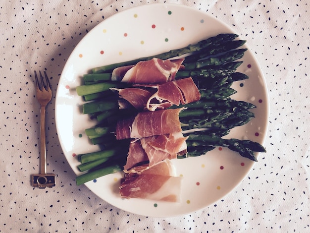 Foto bundles de espárragos atados por prosciutto servidos en un plato