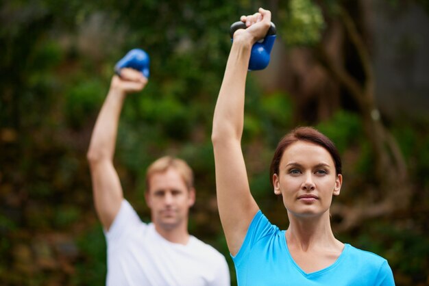 Übung an der frischen Luft Aufnahme eines Mannes und einer Frau mit Kettlebell-Gewichten in einem Übungskurs im Freien