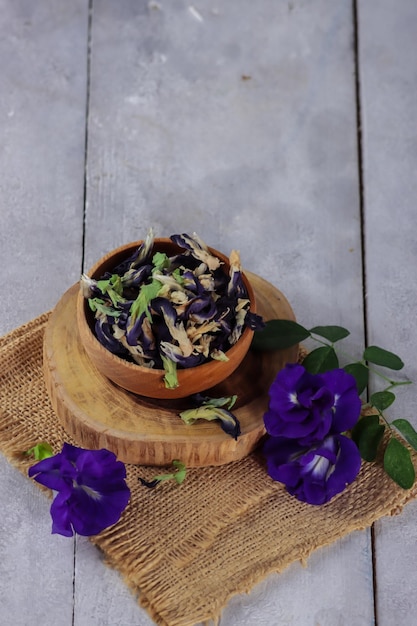 Bunga telang oder Schmetterlingserbsenblumen Clitoria ternatea im Korb auf Holzschwarzgrund