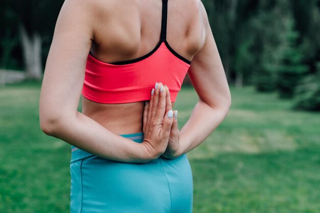 Übungen für die richtige Körperhaltung Körper einer jungen Frau mit hinter dem Rücken gefalteten Handflächen in Asana-Pose Paschima Namaskarasana