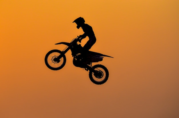 Übungstag, Silhouette eines Motorrad-Motocross-Springens auf Sonnenuntergangshintergrund.