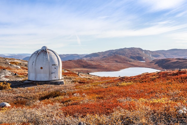 Búnker estadounidense de metal y paisaje de tundra naranja groenlandés de otoño con lagos y montañas en el fondo Kangerlussuaq Groenlandia