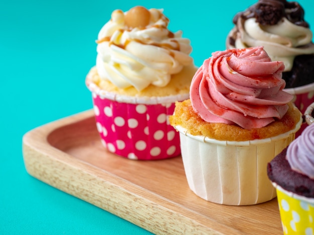 Bunt vom selbst gemachten kleinen Kuchen im hölzernen Behälter auf grünem Hintergrund