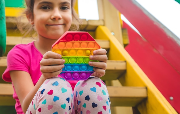 Bunte Antistress sensorische Spielzeug zappeln Push Pop es in Kinderhände. Selektiver Fokus. Natur.