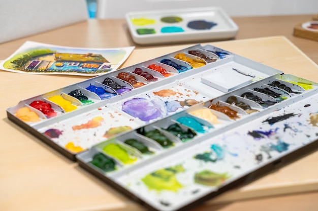 Bunte Aquarellpalette auf dem Tisch mit Aquarellset Selektiver Fokus