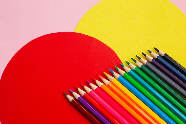 Bunte Bleistifte des Regenbogens auf kreativem farbigem Hintergrund. Kunstvermittlungskonzept.