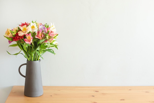 Bunte blumen in einer zementvase auf einem holztisch