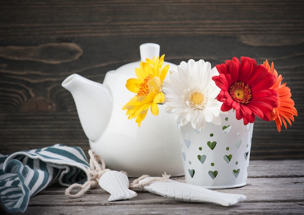 Foto bunte blumen und teekanne auf dunkler holzoberfläche