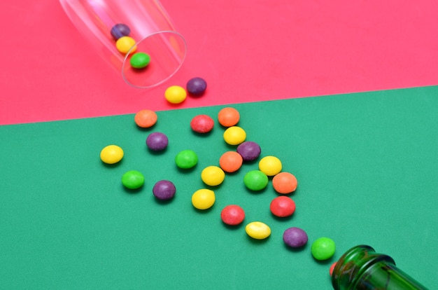 Bunte Bonbons, Flasche und Glas auf hellem Hintergrund