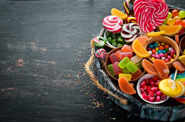 Bunte Bonbons, Gelee und Marmelade in einer Holzkiste Süßigkeiten auf dem alten Hintergrund, Ansicht von oben, freier Kopierraum