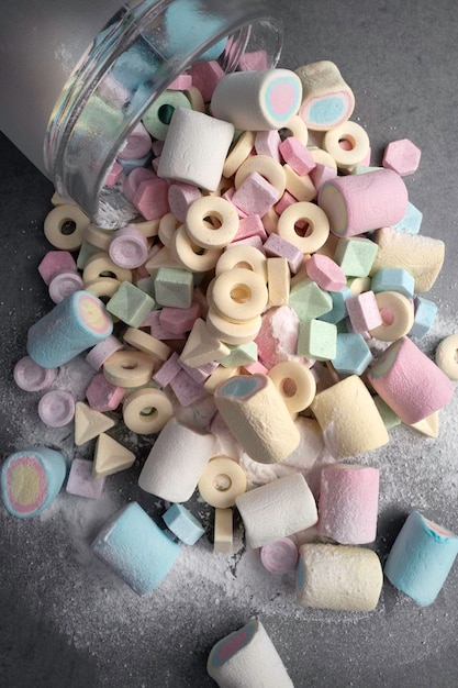 Bunte Bonbons und Marshmallow in Kinderhänden und Glas