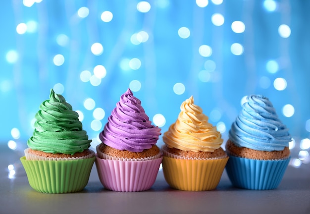 Bunte Cupcake-Glasur in einer Reihe auf glitzerndem Hintergrund