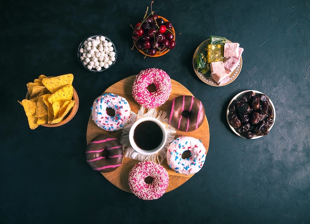 Bunte Donuts auf einem schwarzen Tisch. Draufsicht