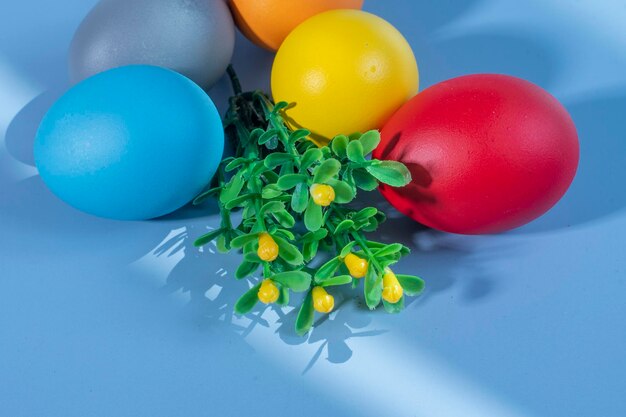 Bunte Eier, die Ostern auf einem bunten Hintergrund und Blumen symbolisieren