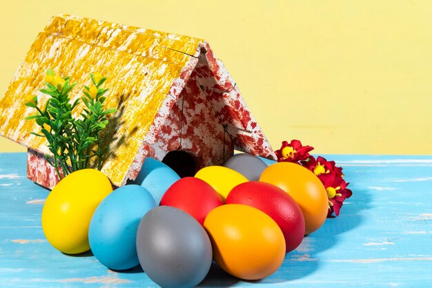 Bunte Eier, die Ostern mit einem Spielzeughaus symbolisieren, blüht wie ein Garten