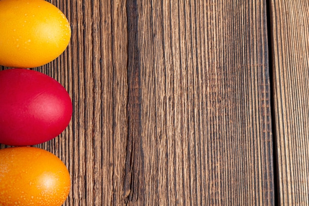 Bunte Eier für Ostern auf einem braunen Holz mit Kopienraum