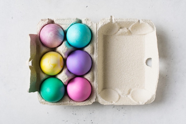Bunte Eier im Karton Ostern- und Frühlingsthema auf Draufsicht des weißen Hintergrundkopienraumes