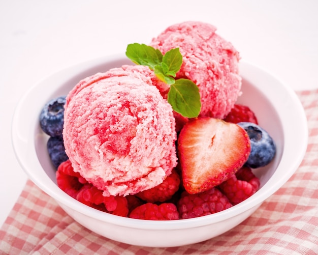 Bunte Eiscreme mit Mischbeeren und verschiedenen Früchten gründete auf weißem Hintergrund.