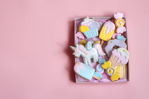 Bunte festliche Lebkuchen in verschiedenen Formen mit Glasur auf rosa Hintergrundkopierraum bedeckt.