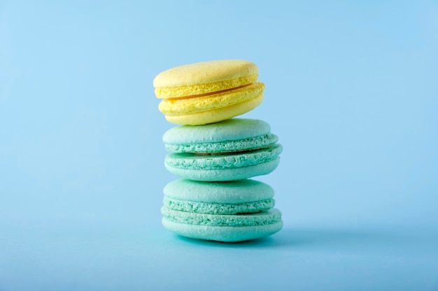 Bunte französische Macarons Cookies Makronen auf blauem Hintergrund Dessert vegetarische Süßigkeiten Nahaufnahme gestapelt Gleichgewicht