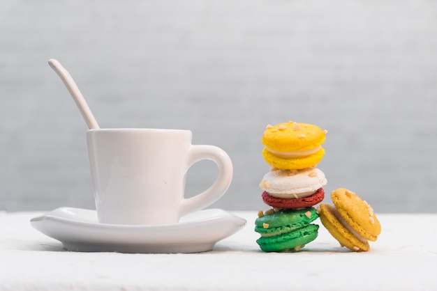 Bunte französische Makronen mit Tasse Kaffee auf weißem Hintergrund