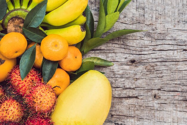 Bunte Früchte auf dem weißen Holztisch, Bananen, Karambolen, Mango, Papaya, Mandarine, Rambutan, Pamela, Textfreiraum