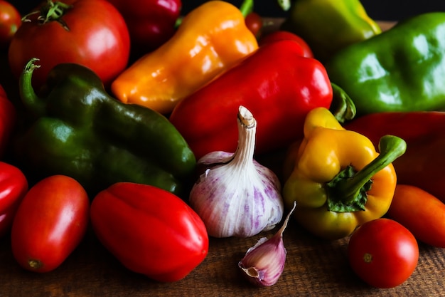 Bunte Gemüse Hintergrund Ernte Frische rohe Paprika Tomaten und Knoblauch auf Holztisch