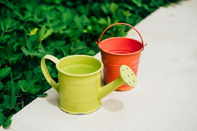 Bunte Gießkannen und Eimer für Pflanzen im Garten