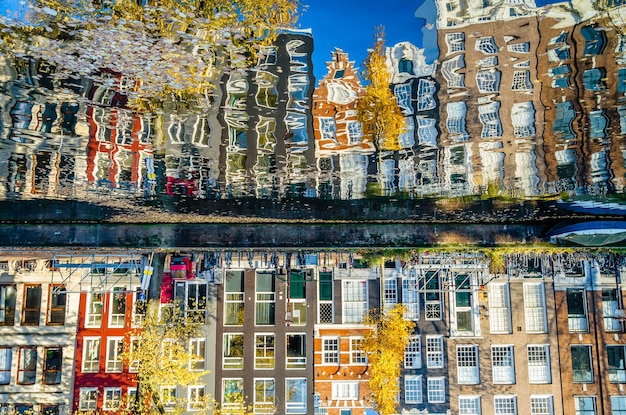 Bunte Häuser entlang des Kanals und ihre Spiegelung im Wasser in Amsterdam, Niederlande