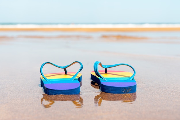 Bunte Hausschuhe am Strand an einem Sommertag Flip-Flops mit Gay-Pride-Flagge