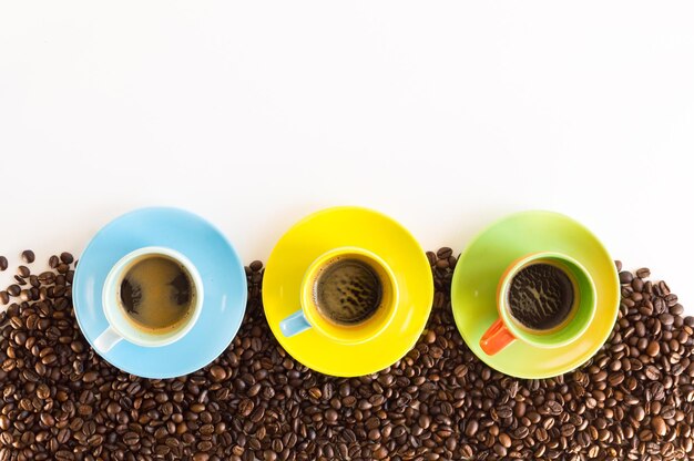 Bunte Kaffeetassen aufgereiht auf Kaffeebohnen isoliert auf weißem Hintergrund für Web-Banner