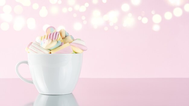 Bunte Kaubonbons der Marshmallows in einer Tasse auf rosa bokeh Hintergrund